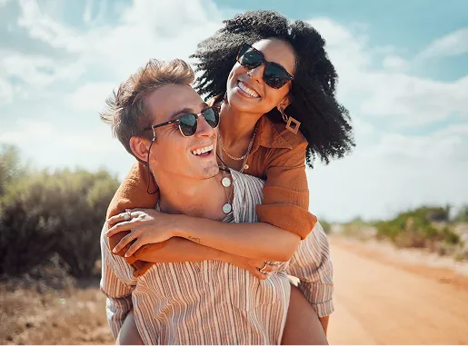 Couple souriant en étreinte avec lunettes de soleil en extérieur ensoleillé
