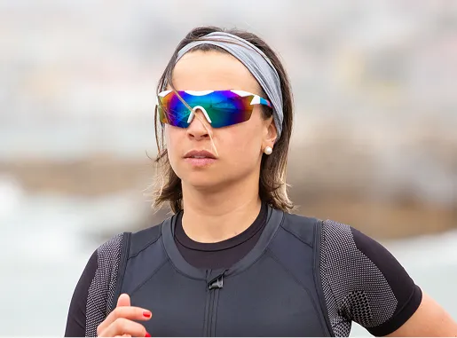 Femme portant lunettes de sport colorées et tenue de running près de l’eau